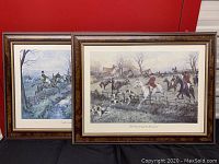 Two framed prints with horse hunting scenes leaning against a red background, showing riders in red coats and dogs.