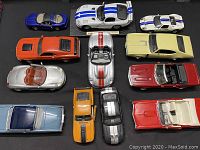 Top-down view of 12 die cast model cars arranged in rows showing various colors and body styles.