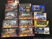 All 12 packaged metal model cars from various brands displayed on black fabric.