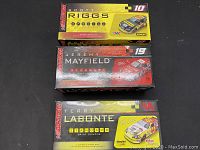 Three boxed Action Racing stock car replicas by Scott Riggs, Jeremy Mayfield, and Terry Labonte shown in original packaging with visible brand and number details.