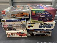 Photo of stacked model kit boxes showing AMT '69 Boss 302, AMT Bigfoot, Revell McDonald's Diorama, Bburago Dodge Viper GTS, Tamiya Volkswagen New Beetle, Monogram 59 Chevy Impala.