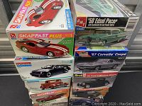 Seven sealed plastic model car kits stacked, titles visible include '97 Dodge Viper GTS, '58 Edsel Pacer, '67 Corvette Coupe, '32 Ford 3-Window Coupe, and others