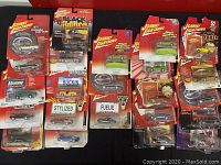 Overview of lot showing multiple Johnny Lightning packaged die-cast cars including various models and series with all original packaging in visible but poor condition.