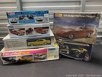Overview of six stacked plastic model car kits including brands and model types visible on packaging.