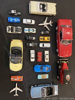 Top view of all die cast replica vehicles and airplanes arranged on black cloth.