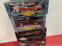Photo of three American Muscle die cast metal replica cars stacked in packaging, showing labels and overall condition.
