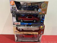 Full view of the four boxed die cast cars stacked: PT Cruiser Convertible Study, Ford Mustang GTA Fastback, Chevrolet Bel Air, and a red car.
