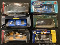 Top down view showing six die cast replica cars in original packaging, some packaging damaged or worn.