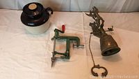 Photo showing the three items: ceramic bean pot, green apple peeler, and antique bell with chain