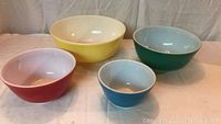 Full set of four vintage Pyrex mixing bowls, showing all from above and front-facing angles.