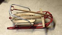 Side and angled views of the child's sled showing metal and wood construction and condition.