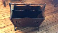Top view of antique wooden magazine rack showing two fabric magazine pockets and floral cut-out side panels