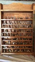 Full view of wooden display case without glass showing multiple shelves filled with small Tetley Tea figurines.
