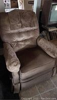 Full view of taupe reclining rocking chair showing cushioned seat, padded armrests, and button-tufted backrest.