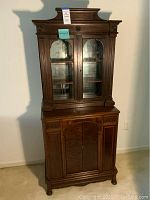 Full frontal view of vintage wooden hutch showing glass doors on upper cabinet and solid doors below.