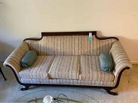 Front view of vintage parlor sofa showing three upholstered removable cushions and two green bolster pillows.