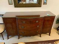 Front view of the wooden buffet showing three rounded front drawers and two cabinet doors on each side.