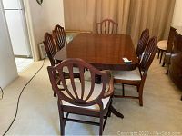 Full view of wooden rectangular dining table with two armchairs and four side chairs around it.