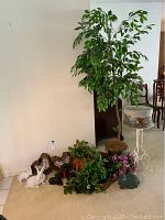 Full view of artificial tree, assorted plants, and ceramic figures grouped near wall