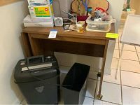 Paper shredder with attached waste bin and wooden sofa table visible behind shredder