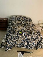 Full assembled bed with dark floral bedding on bed frame, shows overall set up and style