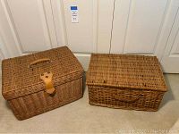 Pair of decorative wicker storage baskets placed on carpet in front of white doors, showing overall shape and size.