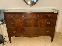 Front view of vintage wood dresser with five drawers and brass handles.