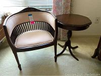 Photo showing the vintage upholstered barrel chair with wooden spindle back and pedestal side table beside it.