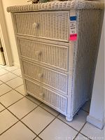 Front angle view showing four white wicker drawers and rounded knobs.