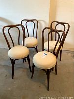 Front view of the 4 bentwood chairs with beige upholstered seats arranged in a semicircle showing wood frames and cushions.