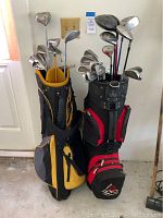 Full view of two golf bags each filled with golf clubs including irons, woods, and putters.