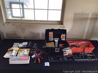 Wide shot of all items on a table including toolboxes, wires, hardware, and antennas.