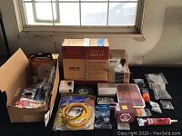 Wide shot showing full lot of home repair accessories including large box of Ethernet cable, buffing wheel, hardware boxes, and smaller packaged items in cardboard boxes.