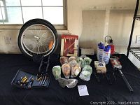 Full lot overview on black table including tires, bottles, goggles, tools, and boxes