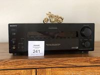 Front view of Sony Digital Audio/Video Control Center with collectible mini-clock on top and maxsold lot sign in front.