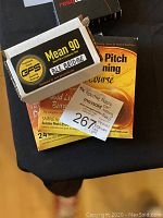 Photo showing Mean 90 black bridge guitar accessory packaging box and Relative Pitch Ear Training SuperCourse CD packaging along with MaxSold lot sticker.