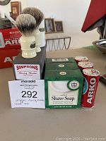 Photo showing two Simpsons shaving brushes with cream handles and best badger bristles next to seven shaving soaps including four green boxes of VDH and three red Arko sticks.