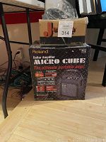 Photo of the Roland Micro Cube guitar amplifier in its unopened original box, showing product graphics and branding.