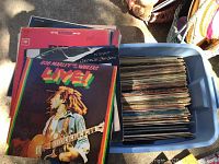 Photo showing the top visible LP record with Bob Marley & The Wailers 'Live!' album cover on a stack of vinyls inside a blue plastic tote.