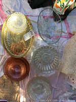 Top view showing an oval clear glass platter, a round clear serving bowl, two rose-tinted plates, and one rose-tinted bowl with various textured designs.