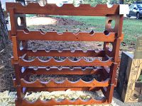 Wooden wine rack displaying horizontal slots for wine bottles, tiered in natural wood color with some visible wear and nicks.