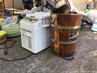 Photo showing Hitachi bread maker and Frost King wooden ice cream maker bucket outdoors with other household items in background
