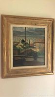 Front view of the oil painting showing the cityscape with architectural elements through a window in a wooden frame.