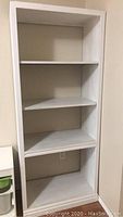 Front view of the white wooden bookshelf showing four shelves and clean finish.
