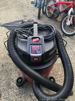 Red Craftsman XSP shop vac with black hose coiled on top and power cord wrapped.