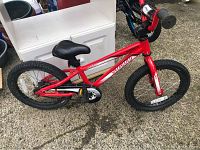 Side view of the red Specialized Hotrock kids bicycle showing frame, tires, pedals, and saddle