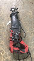 Skil sawzall reciprocating saw showing side profile, black and red body with attached blade and power cord coiled around the tool.