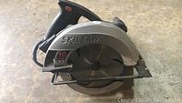 Front side view of Skilsaw circular saw showing 10 inch blade and handle with trigger.