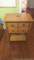 Front view of wooden side table showing four drawers with round knobs and lower shelf.