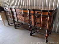 Full view of the carved wooden buffet hutch showing multiple drawers and carved legs.